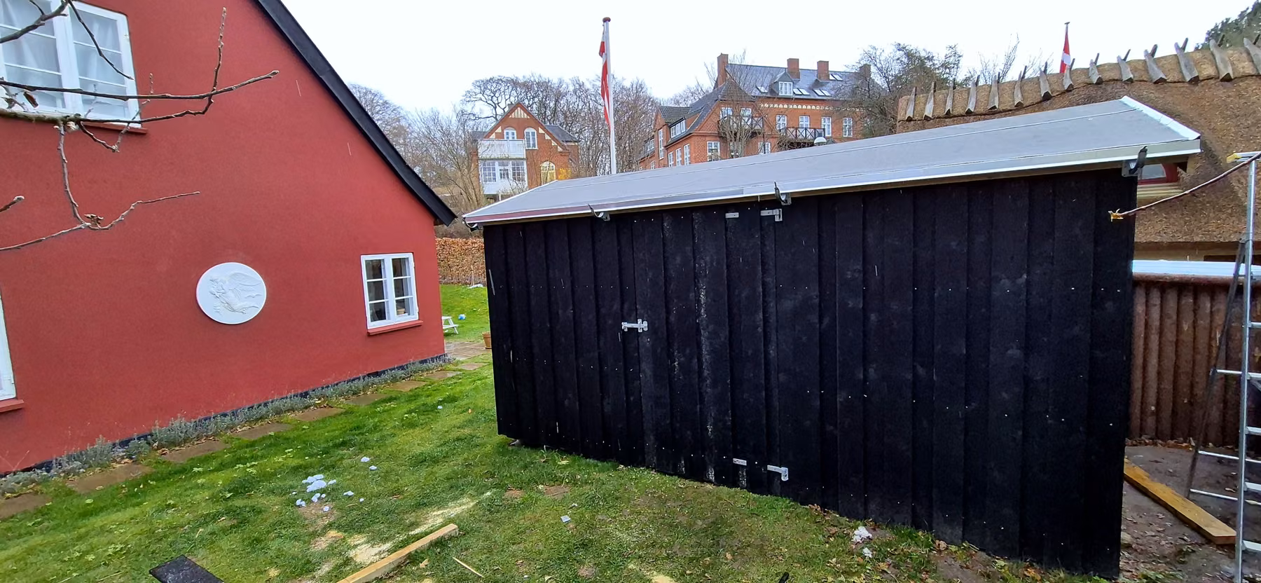 Skuret set fra siden med haven og stråtaghuset bagved